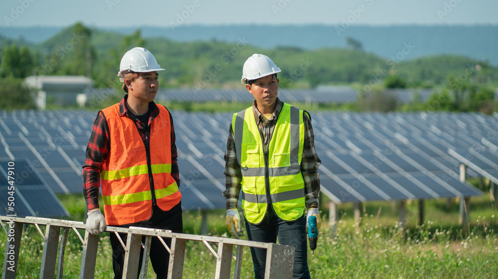 Concept: Renewable Energy. Team of engineers working to check the system through the phone. Photovoltaic for clean energy production. Innovate green energy for life on solar farms Concept: Renewable Energy. Team of engineers working to check the system through the phone. Photovoltaic for clean energy production. Innovate green energy for life on solar farms