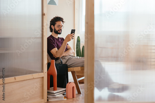 Hispanic man using smartphone in workplace photo