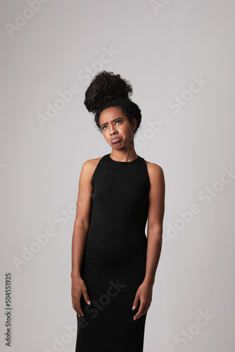 Young African American woman poses on white wall and making face grimace. 