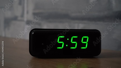 6 am at the digital alarm clock on the table in bedroom. Clock ringing and wakes up us early in the morning. It's time to waking up and go to work. closeup morning concept.