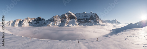 Snowy alpine landscape and sea of fog panorama.