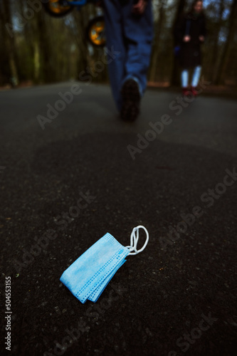 A dirty mask lies on the sidewalk. Disposal of disposable masks. © artdolgov