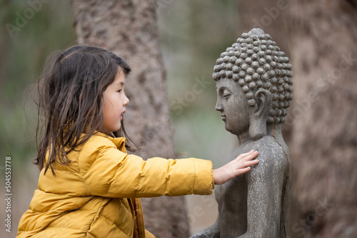 Child outside with buddha statue photo