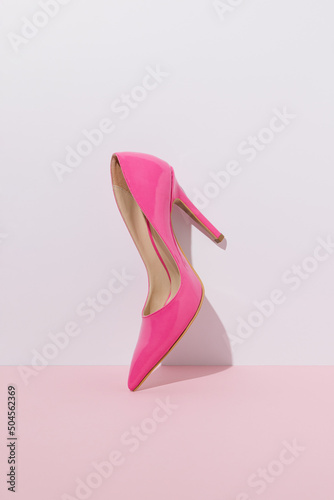 Pink high heel against a pastel wall.