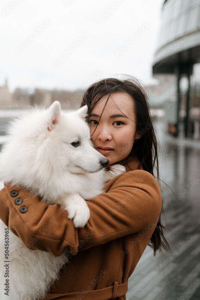 Woman with her dog in her arms looks into the camera