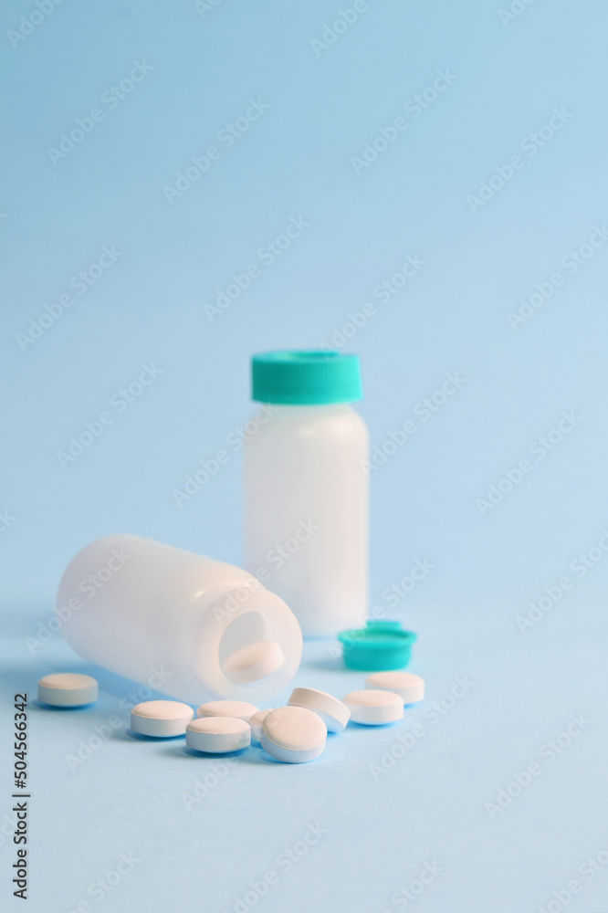 Close up, white round tablets and small bottle on light blue background. Close up, white round tablets and small bottle on light blue background.