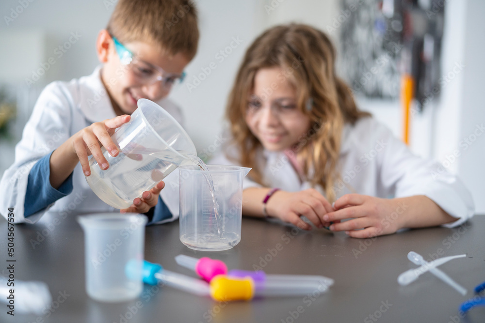 Girl and boy pouring chemicals into jug Girl and boy pouring chemicals into jug