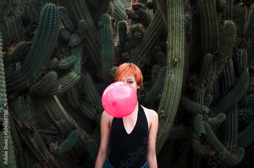 Woman hiding behind balloon surrounded by cactus  photo