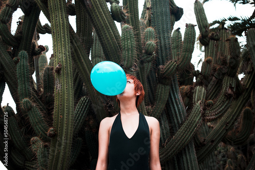 Woman inflating a balloon surrounded by cactus