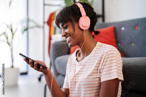 Relaxed lady using cellphone and headphones at home photo