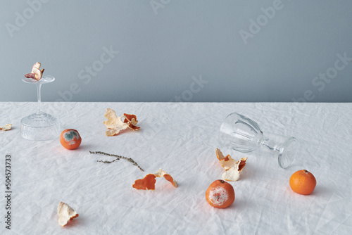 Rotten Tangerines And Glassware On Table photo