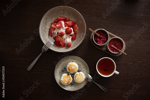 Tasty and healthy breakfast overhead view. Tea with jam, cheese pancakes, burrata salad with tomatoes © ilyaska