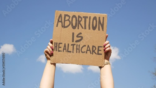 Protester hands holding sign Abortion Is Healthcare. People with placard supporting abortion rights at protest rally demonstration.