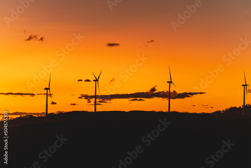 Sunset with wind towers rotating and generating energy. 