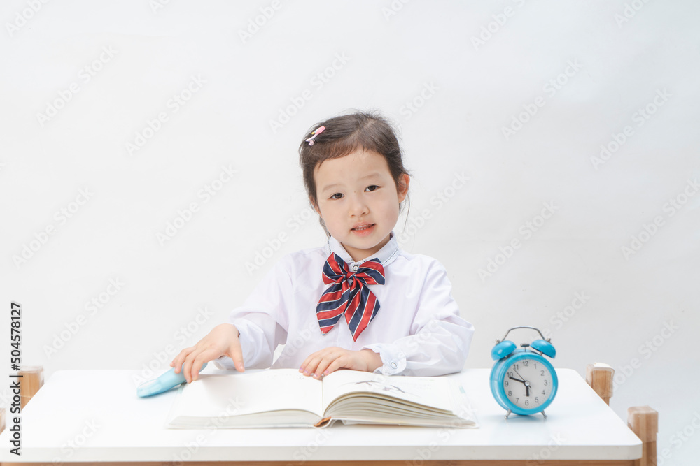 The little girl in school uniform is doing her homework The little girl in school uniform is doing her homework