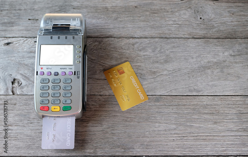 Credit card reader machine and credit card on wood background