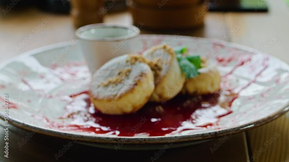 two young happy women enjoy delicious syrniki with jam, eat it with a fork in a beautiful cool place in hot summer. two young happy women enjoy delicious syrniki with jam, eat it with a fork in a beautiful cool place in hot summer.