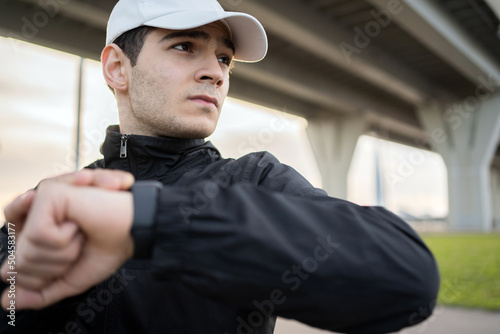 A strong male athlete uses a smartwatch to count calories and pulse.