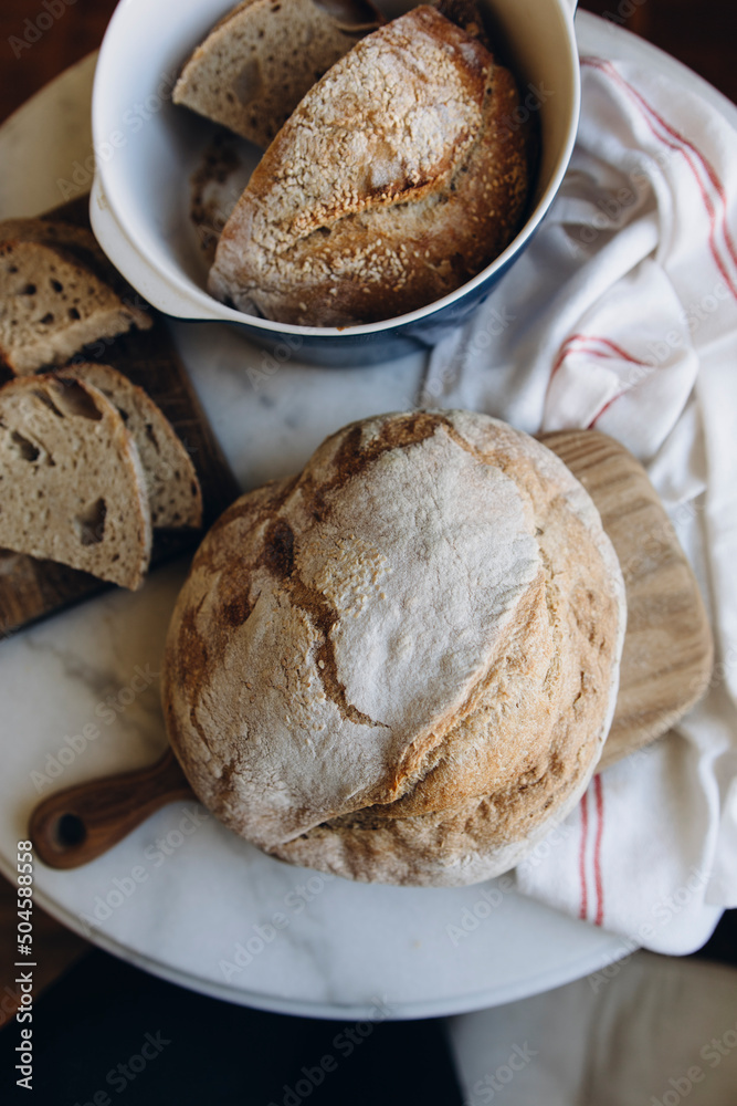 Naklejka premium round freshly baked bread top view. sourdough bread is on the table. whole and sliced bread.