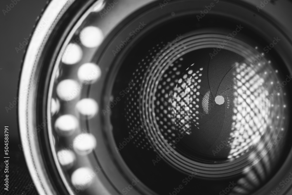 Professional camera photo lens. Details of glass, layer of enlightenment, aperture petals. Light reflections from modern diode lamps. The concept of making visual content. Black and white. Professional camera photo lens. Details of glass, layer of enlightenment, aperture petals. Light reflections from modern diode lamps. The concept of making visual content. Black and white.