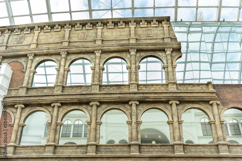 Ruined wall of an old building with columns and mirrored windows.