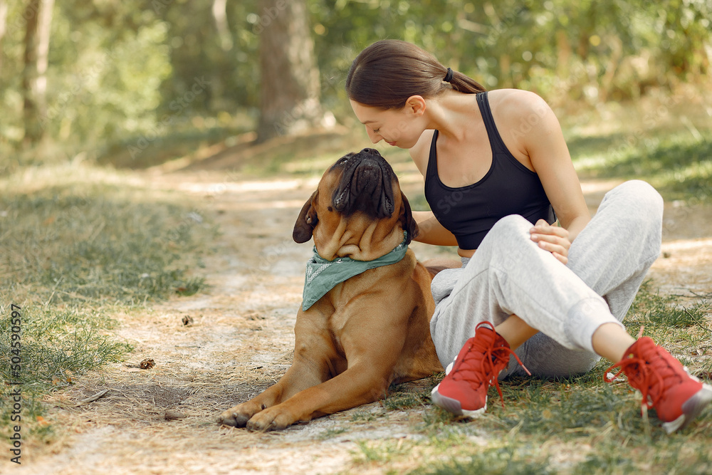 Girl sitting in a forest and playing with dog Girl sitting in a forest and playing with dog