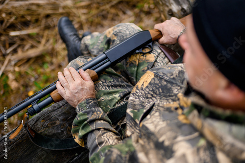 The gun lies on the hunter's lap against the background of uniforms and reeds. High quality photo photo