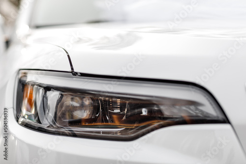 Macro view of modern white car xenon lamp headlight, bumper. Exterior of a modern car