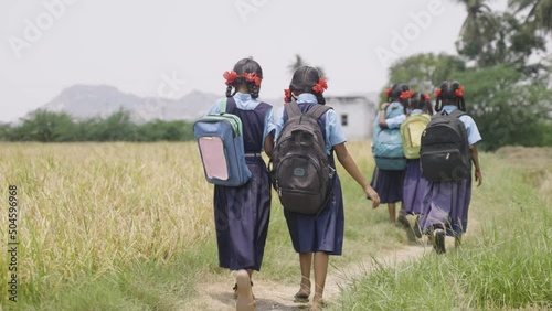 Back view shot of village kids in uniform going home from school after class - concept of education, childhood lifestyle and friendship