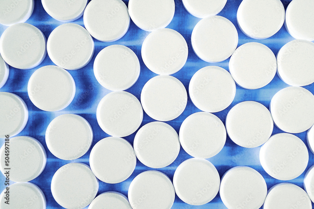 Many round white small tablets photographed close-up.