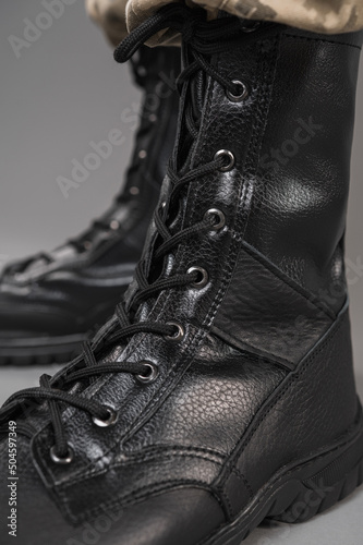 Leather military tactical boots on a Ukrainian soldier on a gray background