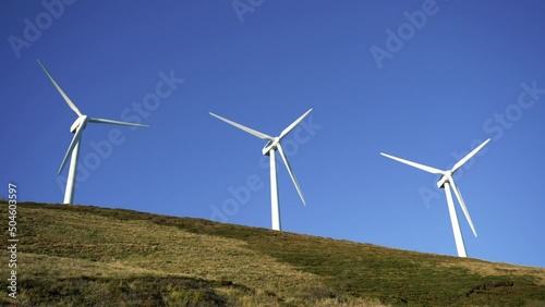 Wind turbines in a wind farm to get clean green energy through the air on top of a mountain on a sunny day. Fight against climate change through renewable energy. It is the future.