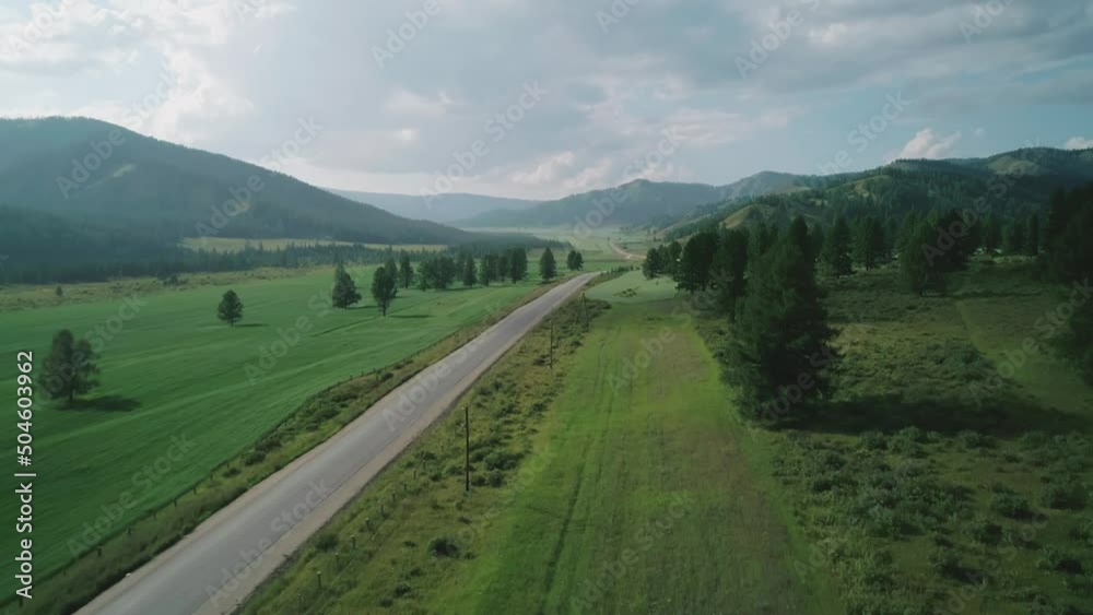 Aerial view of an asphalt road in rural area between green fields and hills Aerial view of an asphalt road in rural area between green fields and hills
