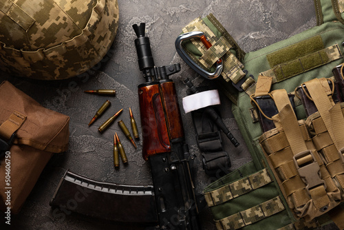Schilderij op canvas Military body armor, helmet and ammunition, a Kalashnikov assault rifle with matrons and a first aid tourniquet