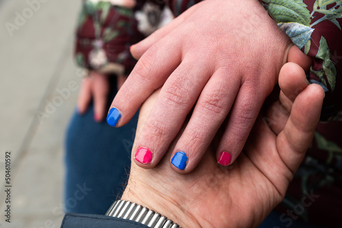 Close up of the small hands of a 39 year old woman with Down Syndrome with painted nails and the big hand of her brother