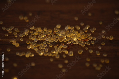 Close up shot of silica gel balls shining like gold in reflected light of the sun on a brown background.