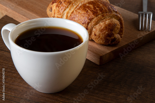 Close-up of croissant with a cup of whole coffee