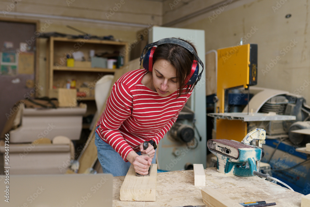 carpenter girl in headphones planing a wooden block