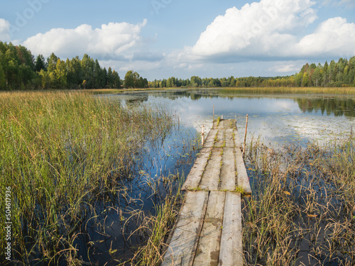 Wooden mooring for boats on Lake Kenozero. Beautiful landscape of clear water and autumn nature. Russia. photo