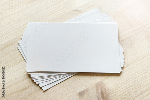 Mockup template with many white cards stacked and rotated on light wooden surface. photo