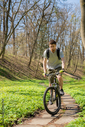 The guy rides a bike through the forest.