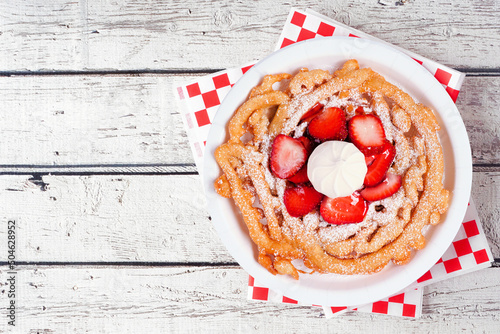 Strawberry funnel cake above view over a white wood background. Traditional summer carnival treat.