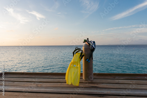Snorkel and scuba diving gear on a deck overlooking the Caribbean Sea at sunset