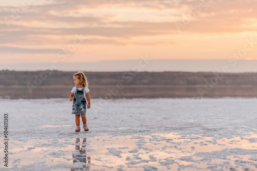 Little girl meets sunset on firth kuyalnik when it's coast is white because of the salt
