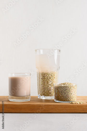 Vegan raw green buckwheat milk on white background. Cooking plant based milk replacer. Vertical format.