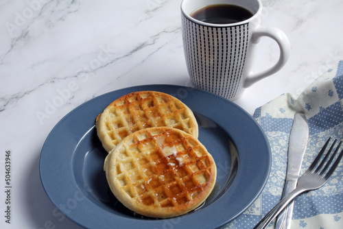 Waffles with butter and syrup, and coffee for breakfast.