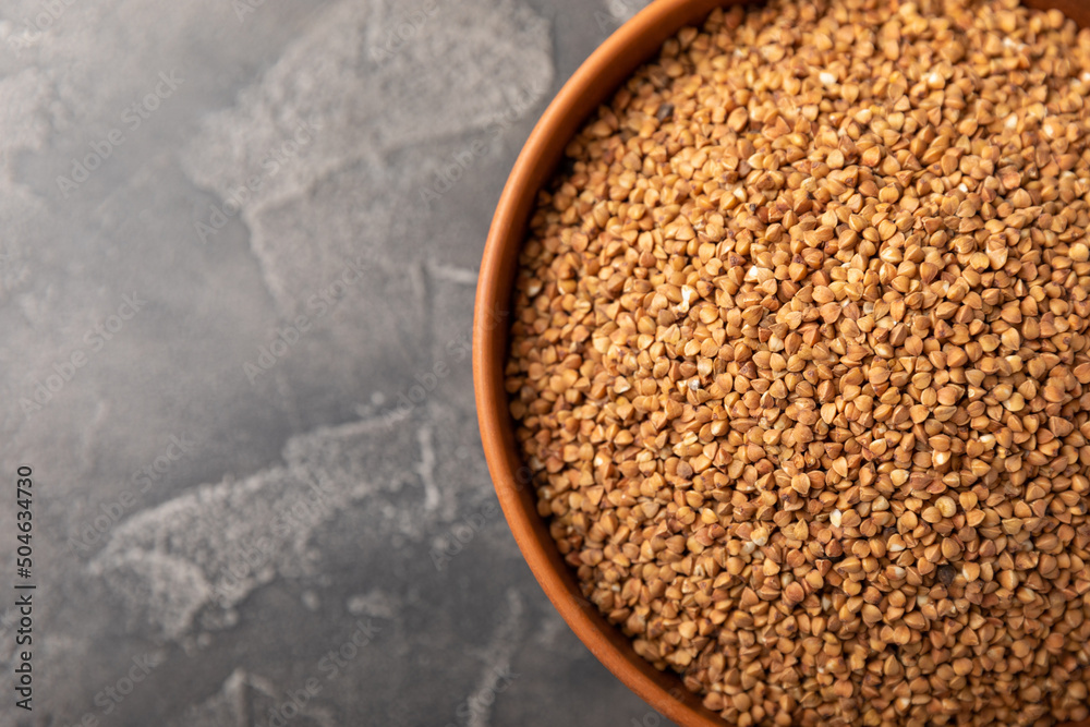 Buckwheat in a bowl on a black marble background. Raw buckwheat. Ingredients for gluten-free porridge.Healthy food. Place to copy. Buckwheat in a bowl on a black marble background. Raw buckwheat. Ingredients for gluten-free porridge.Healthy food. Place to copy.