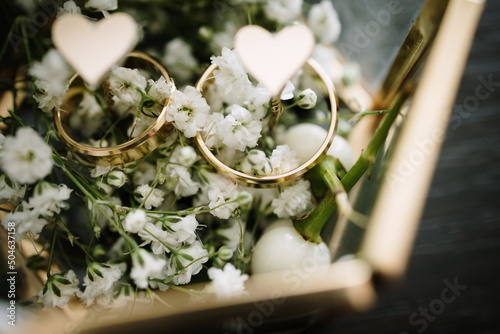 White flowers and two golden wedding rings on flower background