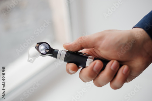 Otoscope on a white background in the hand of an otolaryngologist. Instrument for examining the auricle and middle ear