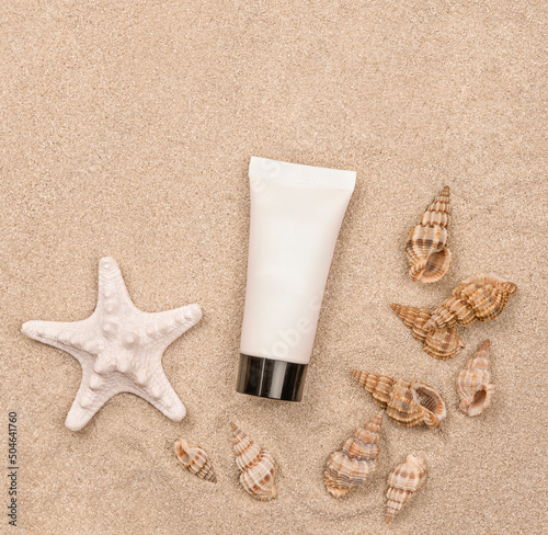 a suntan cream and seashells on sandy background
